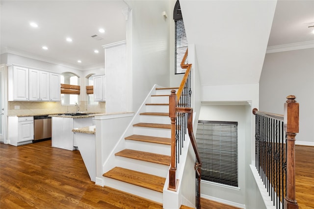 staircase featuring sink, hardwood / wood-style flooring, and ornamental molding