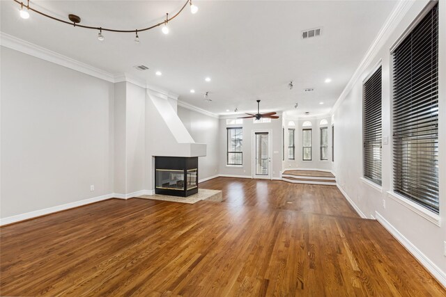 unfurnished living room featuring ceiling fan, hardwood / wood-style floors, a multi sided fireplace, and crown molding