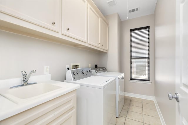 laundry area with cabinets, separate washer and dryer, sink, and light tile patterned floors