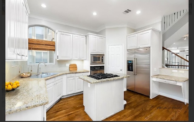 kitchen with appliances with stainless steel finishes, a center island, sink, and white cabinets