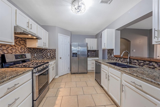 kitchen with white cabinets, stainless steel appliances, light tile patterned floors, light stone counters, and sink