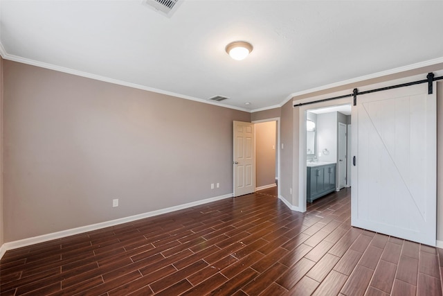 unfurnished bedroom with connected bathroom, crown molding, and a barn door