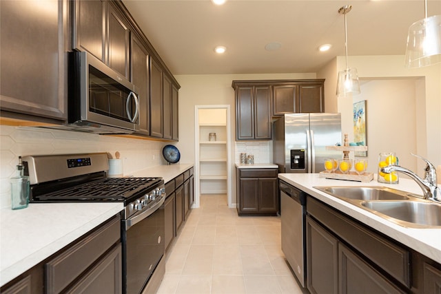 kitchen featuring dark brown cabinetry, sink, decorative light fixtures, and appliances with stainless steel finishes