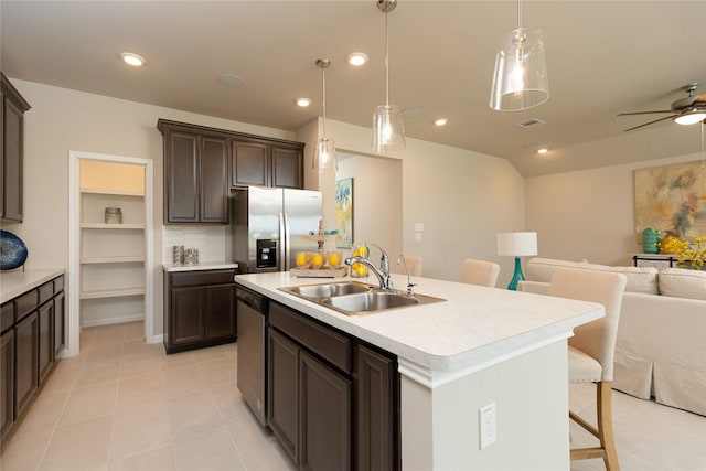 kitchen with decorative light fixtures, sink, a kitchen bar, a kitchen island with sink, and stainless steel appliances