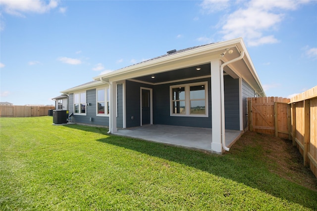 rear view of property with cooling unit, a yard, and a patio area