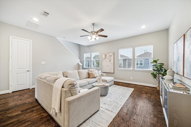 living room with dark wood-type flooring, ceiling fan, and a healthy amount of sunlight