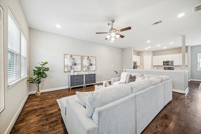 living room with plenty of natural light, ceiling fan, and dark hardwood / wood-style floors