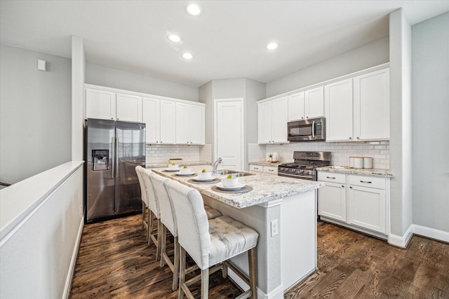 kitchen with a center island with sink, white cabinets, and appliances with stainless steel finishes