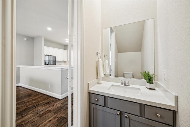 bathroom with toilet, wood-type flooring, and vanity