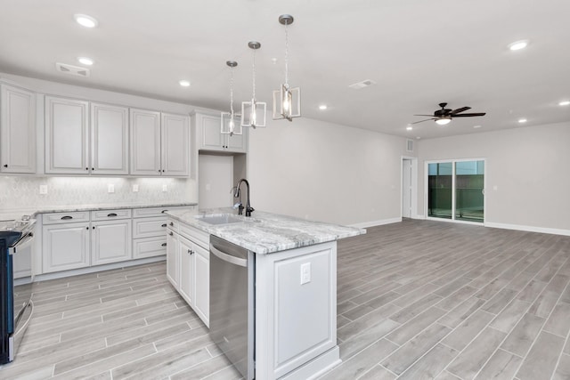 kitchen featuring white cabinets, a center island with sink, appliances with stainless steel finishes, and sink