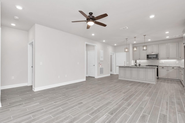 unfurnished living room with ceiling fan, light hardwood / wood-style floors, and sink