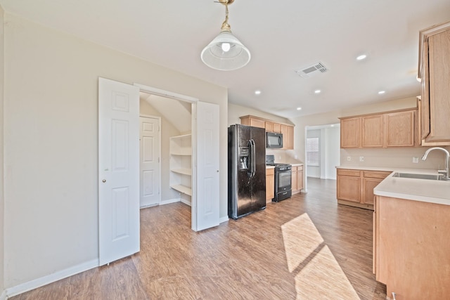 kitchen with sink, decorative light fixtures, light brown cabinets, light hardwood / wood-style floors, and black appliances