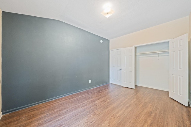 unfurnished bedroom with light hardwood / wood-style floors and vaulted ceiling