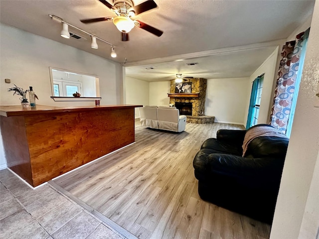 living room featuring a fireplace, light wood-type flooring, rail lighting, and ceiling fan