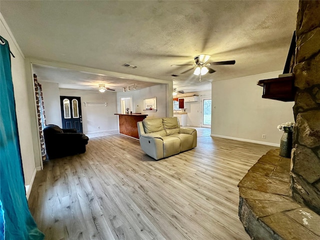 living room featuring a textured ceiling, ceiling fan, and light hardwood / wood-style flooring