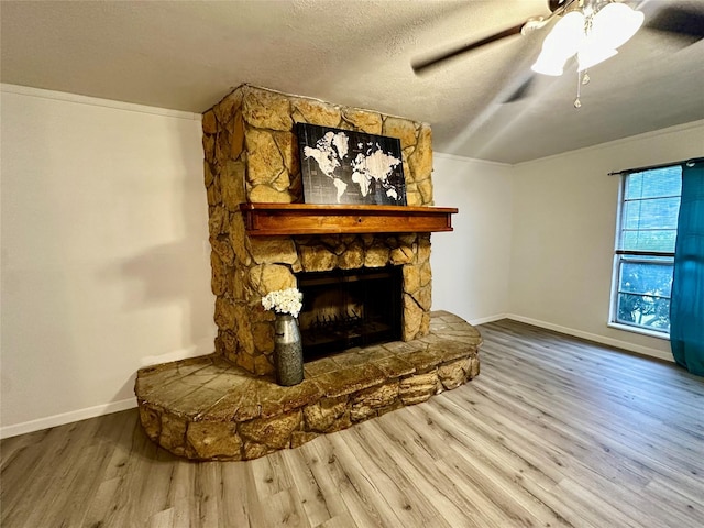 living room featuring ceiling fan, a fireplace, hardwood / wood-style floors, and a textured ceiling