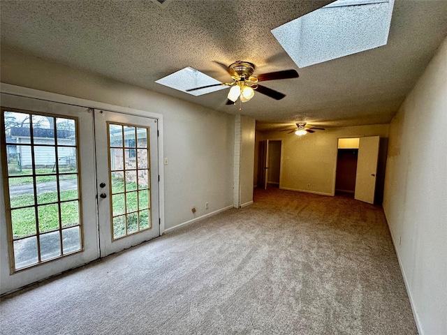 unfurnished room with french doors, carpet, a skylight, and ceiling fan