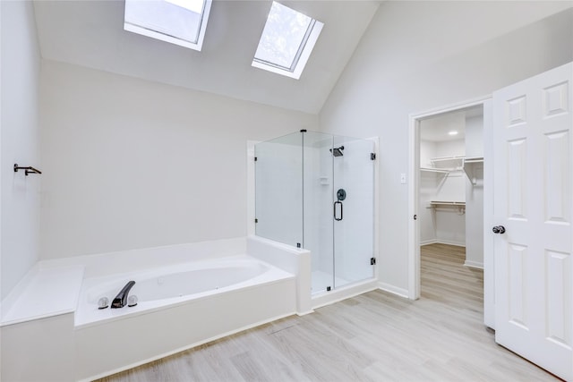 bathroom featuring shower with separate bathtub, hardwood / wood-style floors, high vaulted ceiling, and a skylight