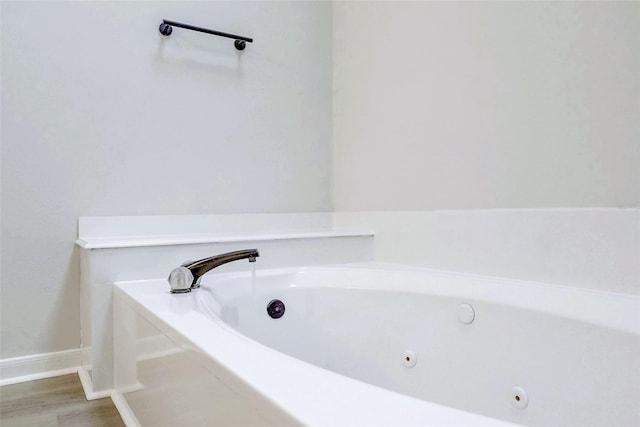 bathroom with hardwood / wood-style floors and a tub to relax in