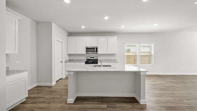 kitchen featuring appliances with stainless steel finishes, an island with sink, dark wood-type flooring, sink, and white cabinetry