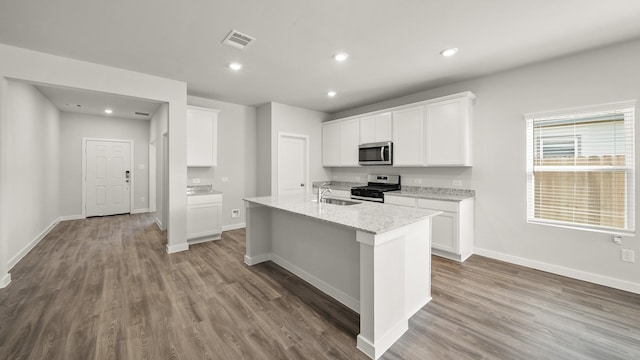 kitchen featuring stainless steel appliances, white cabinets, sink, and an island with sink