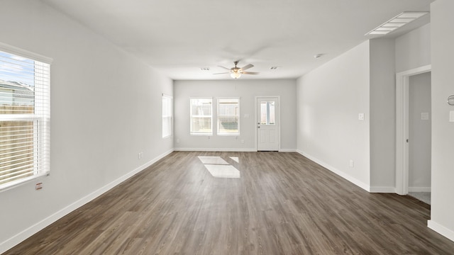 spare room with dark wood-type flooring, ceiling fan, and a healthy amount of sunlight