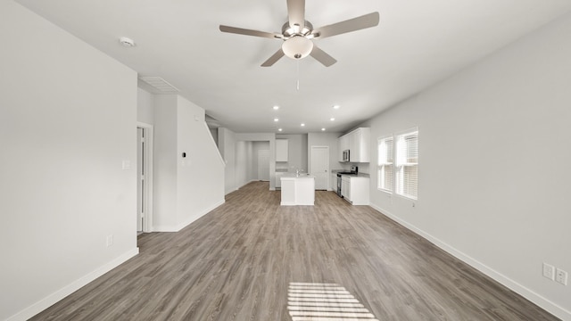 unfurnished living room featuring ceiling fan and hardwood / wood-style flooring