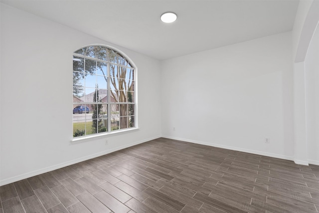 empty room featuring dark wood-type flooring and baseboards