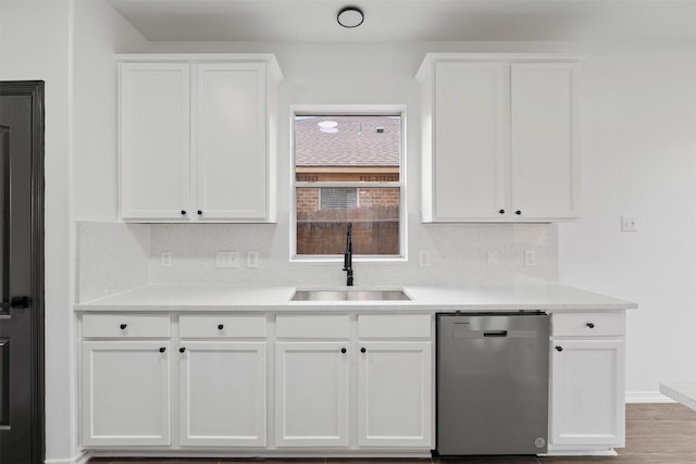 kitchen featuring light countertops, decorative backsplash, white cabinets, a sink, and dishwasher