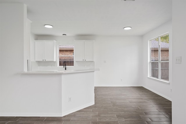 interior space featuring dark wood-style floors, light countertops, decorative backsplash, white cabinets, and baseboards