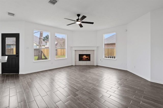 unfurnished living room with dark wood-style floors, a tile fireplace, visible vents, and a ceiling fan