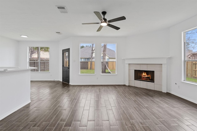 unfurnished living room featuring plenty of natural light, a fireplace, and dark wood finished floors