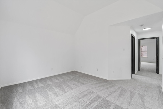 carpeted empty room with lofted ceiling and baseboards