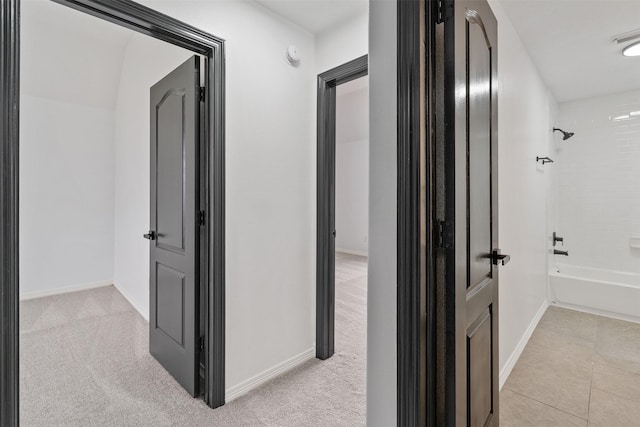 hallway featuring baseboards, carpet, and tile patterned floors