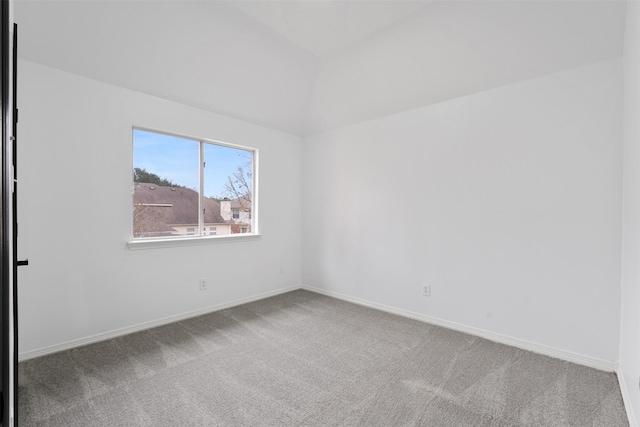 empty room featuring carpet floors, baseboards, and lofted ceiling