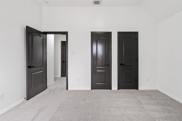 unfurnished bedroom with lofted ceiling, carpet, visible vents, and baseboards