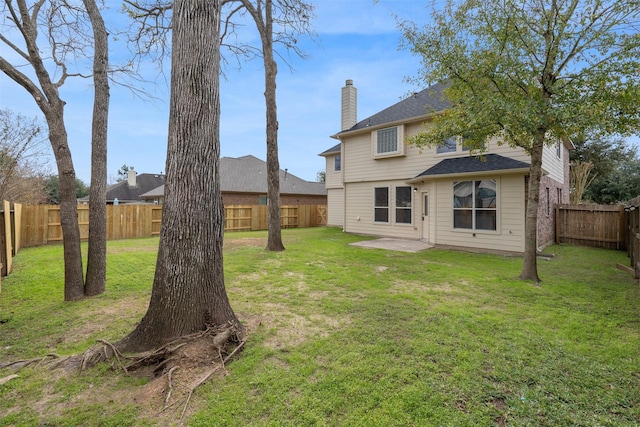 rear view of house featuring a patio area, a fenced backyard, a yard, and a chimney