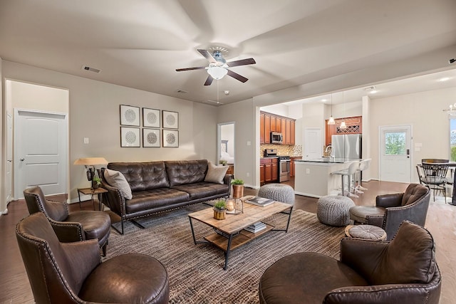 living room featuring hardwood / wood-style flooring, ceiling fan, and sink