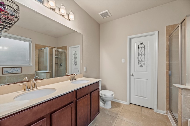 bathroom featuring toilet, a shower with door, vanity, and tile patterned floors