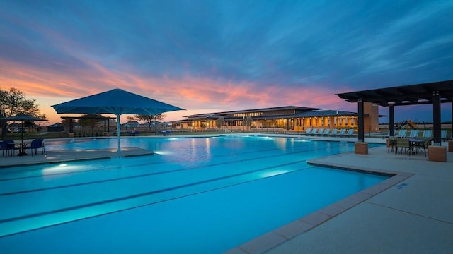 pool at dusk featuring a patio area