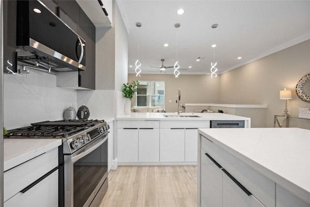 kitchen featuring sink, white cabinets, light hardwood / wood-style floors, tasteful backsplash, and appliances with stainless steel finishes