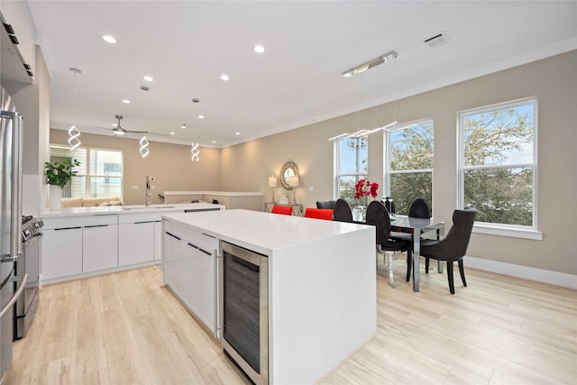 kitchen with a healthy amount of sunlight, white cabinetry, decorative light fixtures, and wine cooler