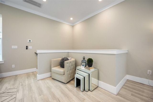 sitting room featuring crown molding and light hardwood / wood-style flooring