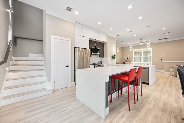 kitchen featuring white cabinets, stainless steel appliances, kitchen peninsula, a breakfast bar, and sink