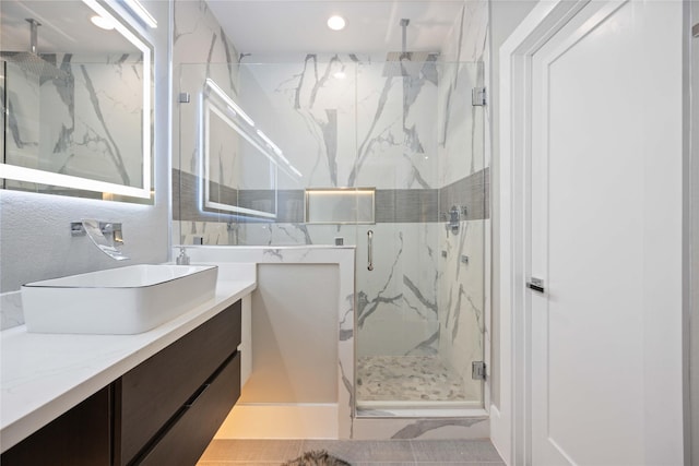 bathroom featuring a shower with door and vanity