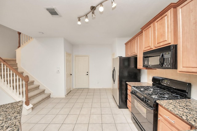 kitchen featuring light tile patterned flooring, decorative backsplash, black appliances, and light stone counters