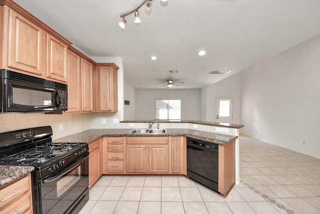 kitchen featuring sink, light tile patterned floors, black appliances, and dark stone counters