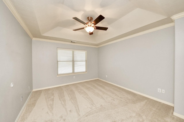 spare room featuring ceiling fan, light carpet, a tray ceiling, and crown molding