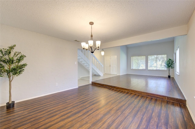 spare room featuring a chandelier, dark hardwood / wood-style floors, and a textured ceiling