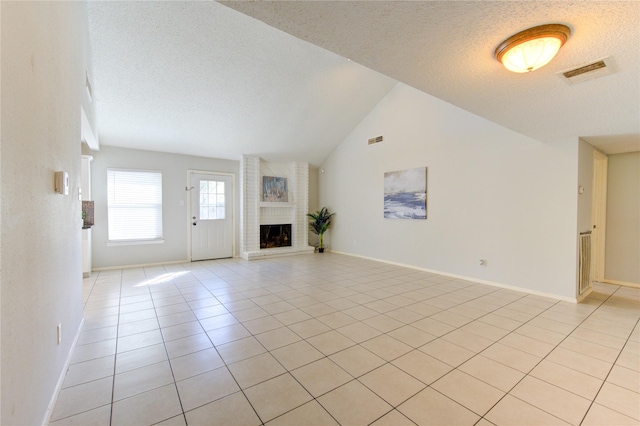 unfurnished living room with vaulted ceiling, a textured ceiling, light tile patterned floors, and a fireplace